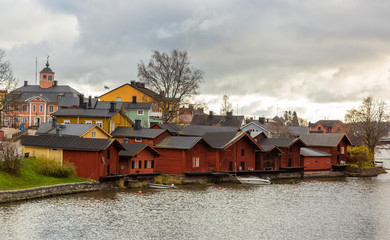Fototapeta premium Porvoo town, Finland. Old red wooden houses on the river coast on a cloudy day