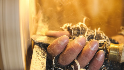 Woodworker cuts wood by chisel.Carpenter handles wood by lathe. Builder works with workpiece in workshop. Making beautiful wooden handmade dish. Production of unusual plate.