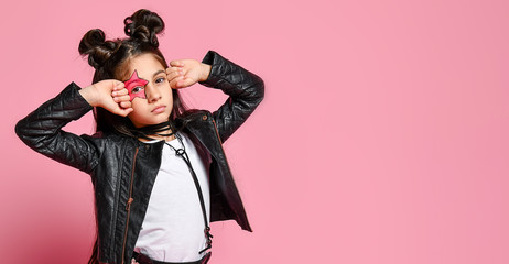 Portrait of a hipster punk girl - dressed in a leather jacket and skirt, black knee-highs and a white T-shirt, with a funny hairstyle and a makeup painted star on the face, points to the head. - obrazy, fototapety, plakaty