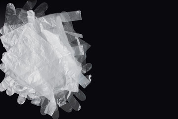 Plastic bag with handles, gloves, on a black background . Used plastic bag for recycling. Concept - ecology, planet pollution with plastic cellophane polyethylene