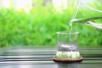 glass of water on background of green leaves