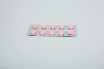 Pink tablet pills in blister , isolated on white background