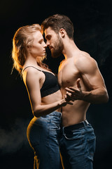 hot man and woman kissing , expressing passionate emotion. close up side view photo. isolated black background. sexual intercourse