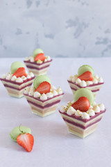 dessert in cups with fresh strawberries and macaroons on a white table