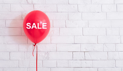 Pink balloon with white text hang out in front of white bricks wall