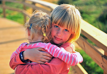Little blond boy hugging his sister outdoors