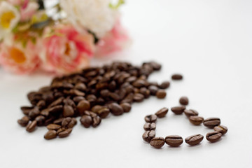 Coffee beans with a bouquet of flowers in the background