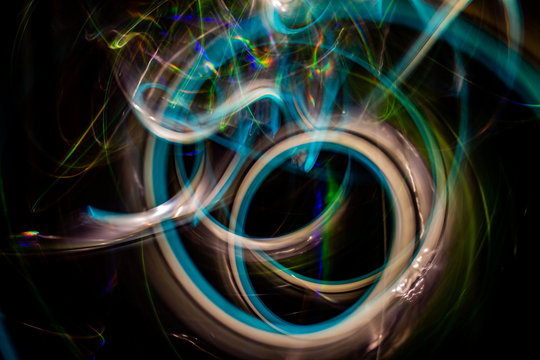 Long exposure photography made with light paint of various colors on neutral black background, waves, curves and swirls, curvilinear or rounded pattern.