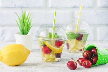 Infused Water with Fresh Organic Fruit Berry Mint. Healthy Eating, Drinking. Vegetarian Diet and Detox Concept. Cup of Lemonade on White Brick Wall Background. Slimming Juicy Beverage