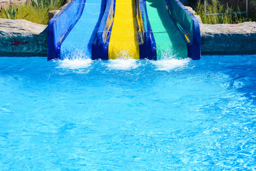 Obraz na płótnie Canvas Multi-colored water slides with water jets in the blue pool