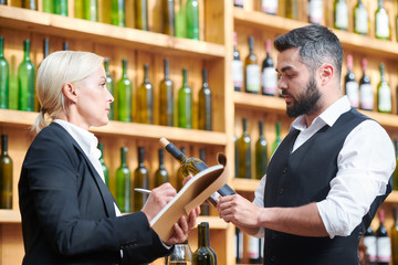 Two colleagues discussing new sort of wine in cellar