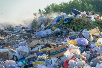 City dump with different garbage burns on a sunny summer day