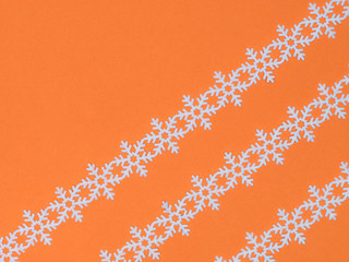 White laces snowflake on orange background. Christmas and New year concept