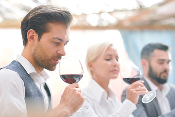 Serious male sommelier smelling red wine from wineglass