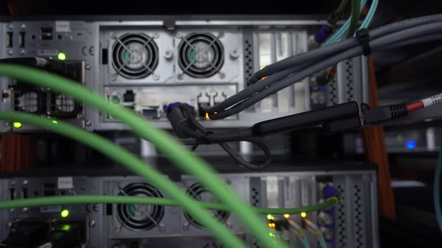 Blinking network ethernet switch with connected cables in server room.