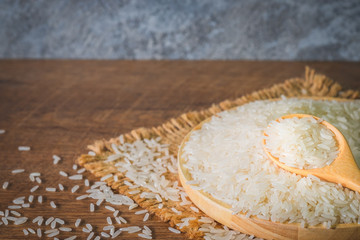 Shot of white Jasmine rice  in wooden spoon with grain and seed on bowl wooden, sack and wood background.