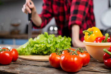 Tomatoes, peppers and greens, lie on a wooden table, ingredients for making salad, close-up of healthy food