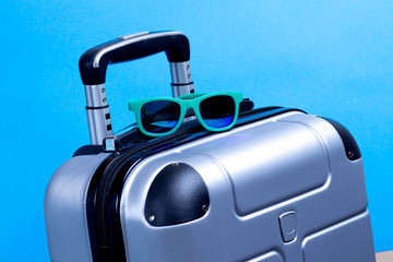 Summer sunglasses and suitcase on blue background. Travel vacation concept