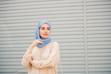 Calm young muslim woman in hijab waiting for taxi or somebody