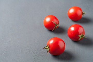 Four whole fresh ripe tomatoes lies on dark cement table. Copy space for text