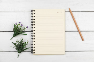 Top view of an open notebook with pencil on white wooden desk