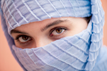 Fototapeta premium Glance of young attractive Muslim female in blue hijab gazing at you