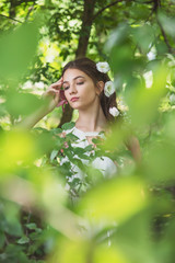 Fototapeta premium beautiful girl with lilies in her hair, flowers in the luxurious dark hair of a young lady
