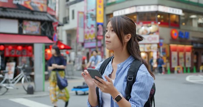 Woman look for a shop on searching with cellphone at outdoor