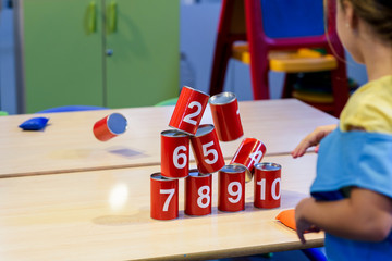 Child throwing a sack to the pile of cans. Child's play. Game of aim.