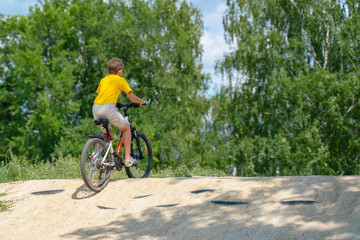 Fototapeta na wymiar A boy on a bike drives up the hill