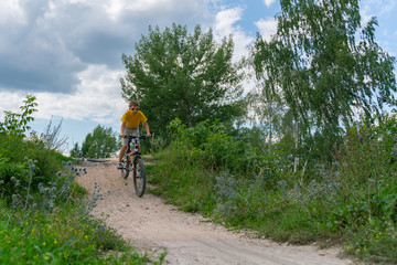 Naklejka premium A boy on a bike down the hill on a forest road