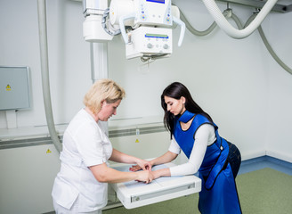 Radiologist and patient in a x-ray room. X-ray of human hand. Classic ceiling-mounted x-ray system.