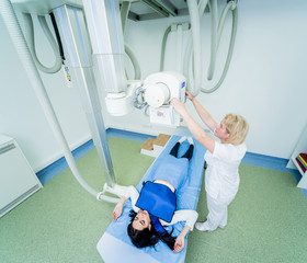 Radiologist and patient in a x-ray room. Classic ceiling-mounted x-ray system.