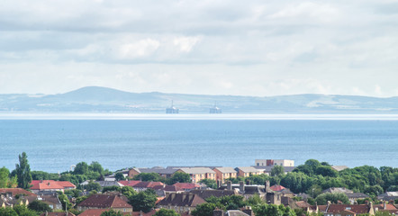 A view of the Coast of fife and two oil rigs with a panomara of the City of Edinburgh in the foreground