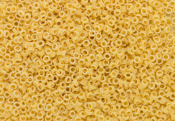 Anellini (anelli, anelletti). Raw dry short Italian pasta in the form of small rings. Ingredient for making soup or garnish. Culinary background texture. Selective focus - 279656072