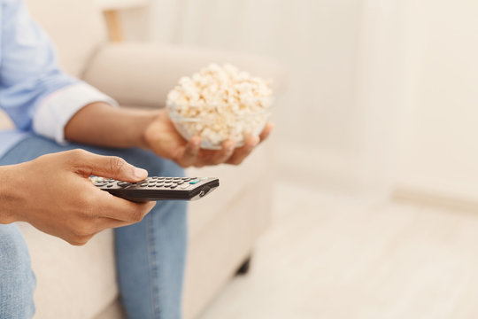 Man holding tv remote controller and popcorn in hands