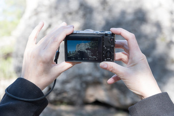 Photograph of rock through a camera and the hands of a woman
