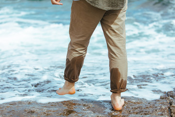 wet man legs in pants walking by sea rocky beach enjoying water