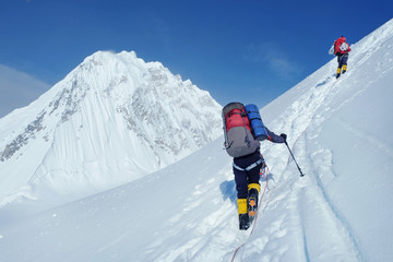 Mountaineer with backpack crossing Khumbu glacier crevasse during ascent on Everest
