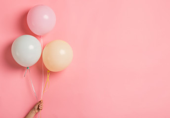 Party balloon bunch in woman hand on pink background