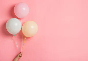 Deurstickers Party balloon bunch in woman hand on pink background © Prostock-studio