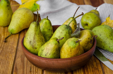 Naklejka na ściany i meble fresh ripe pears in a clay bowl on a dark wooden background. Rustic style