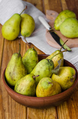 fresh ripe pears in a clay bowl on a dark wooden background. Rustic style