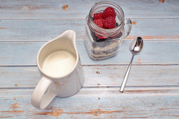 glass jug filled with cereals, raspberries and blueberries