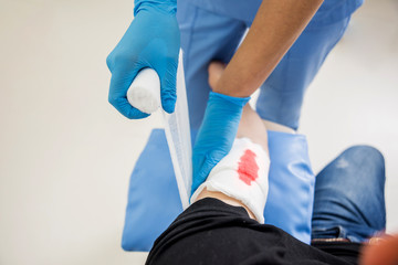 Nurse dressing wound for patient's hand with deep skin cutting.
