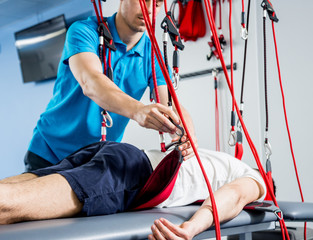 Physiotherapy. Suspension training therapy. Young man doing fitness traction therapy with...