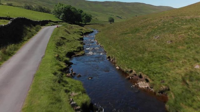 A low altitude, fast speed flyover of Barbon Beck, Carnforth, Lancashire, England. This stunning countryside features a stream running alongside a small country lane.