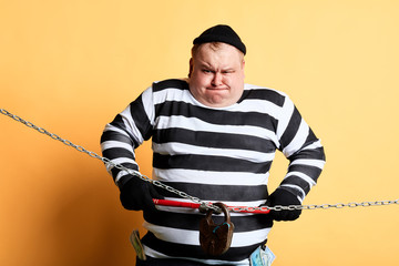 nervous prisoner making effort to cut the chain of the house, close up photo. isolated yellow...
