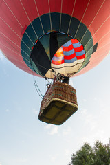 flying balloon with passengers in a basket against the blue sky at the festival of Aeronautics in...