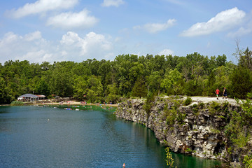 People walking on the cliffs while others enjoy the water and the beach at France Park campground in cass county indiana